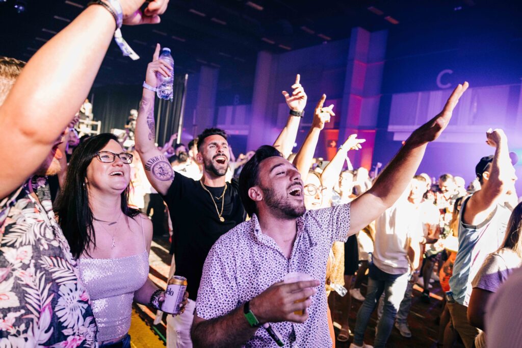 people cheering in the crowd at a music festival
